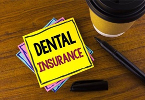 Dental insurance on yellow post it note next to coffee cup