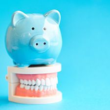 Blue piggy bank on top of a model of teeth