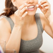 A woman using teeth whitening strips 